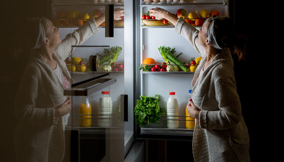 A woman retrieving food from a refrigerator, including celery and red vegetables, illustrating a health-focused lifestyle connected to SteelFit USA's fitness products.