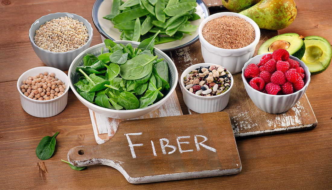 A diverse array of superfoods, including chickpeas, spinach, and raspberries, displayed in bowls on a table, highlighting nutritious, natural ingredients.