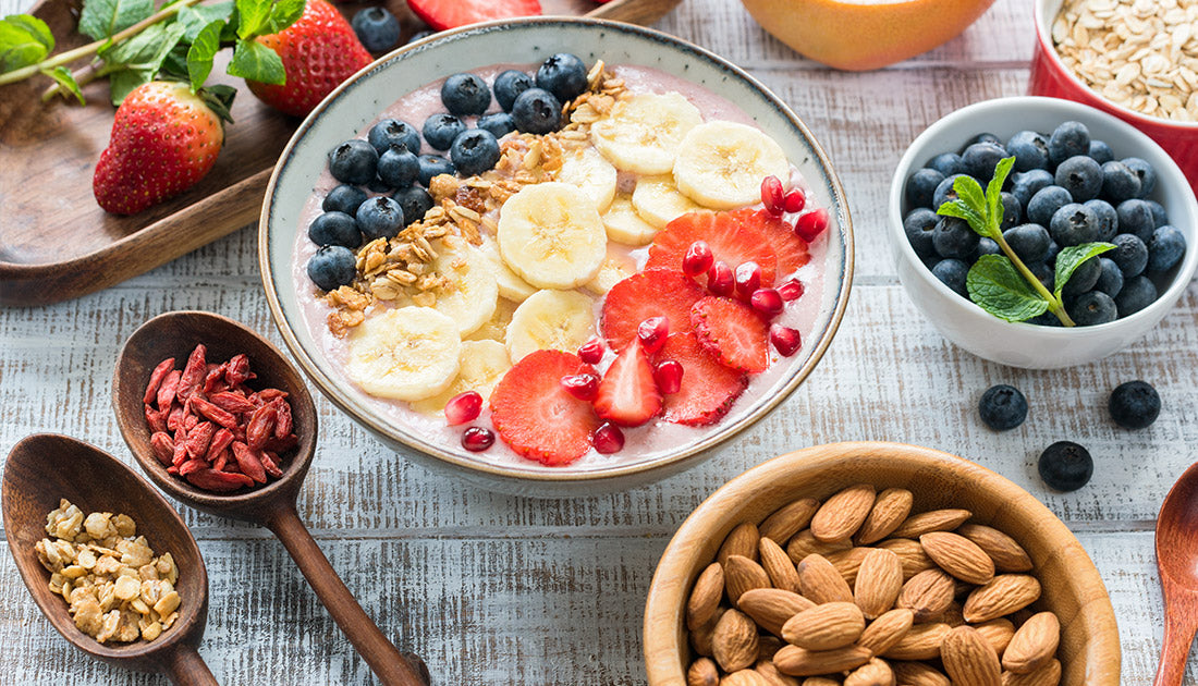 A bowl of fruit, nuts, and oatmeal accompanied by a bowl of blueberries, showcasing nutritious ingredients ideal for fitness and health-focused diets.