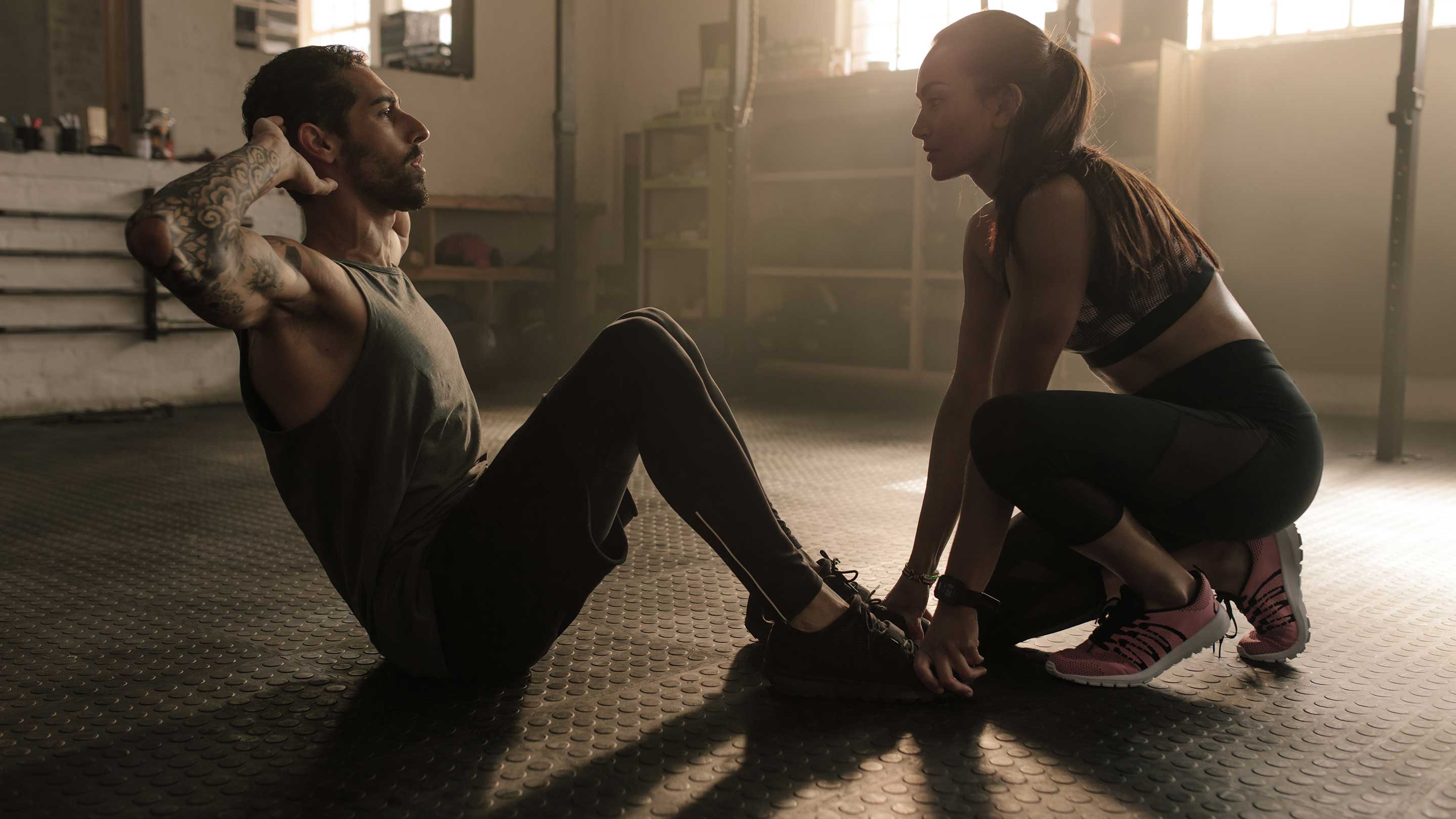 A man and woman sitting on the floor, both in athletic wear, highlighting footwear; aligns with fitness and health goals.