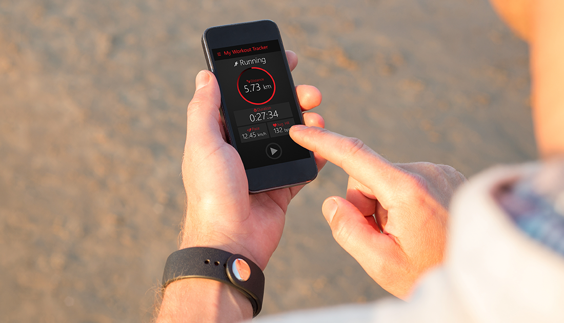 A person outdoors holding a phone displaying a running app, emphasizing fitness tracking, aligned with SteelFit USA's health and fitness focus.