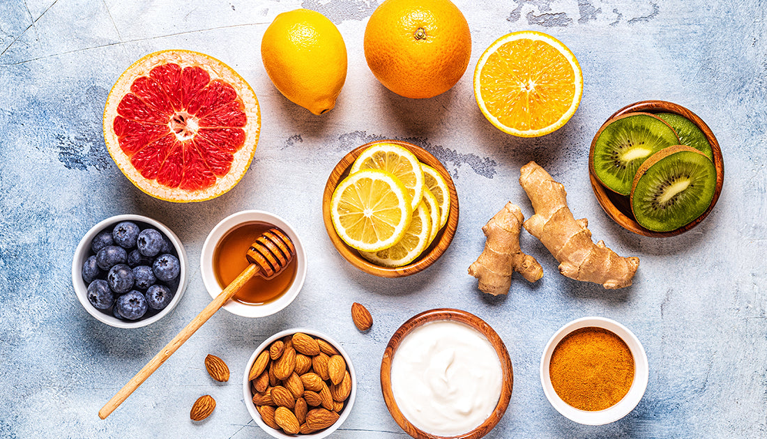 A variety of citrus fruits, nuts, and a bowl of yellow powder, emphasizing natural ingredients for health and fitness nutrition.