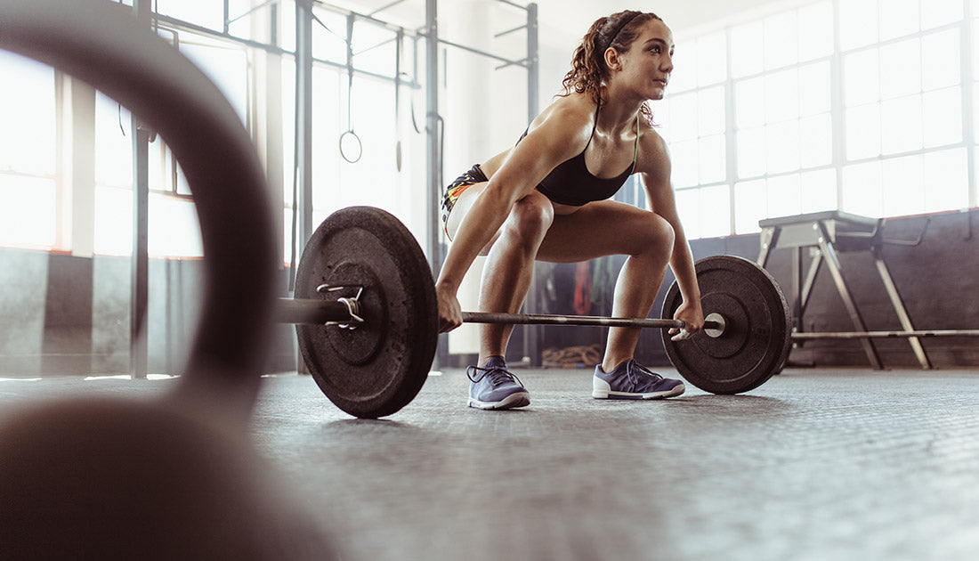 A woman lifting a barbell in a gym, showcasing strength training, related to fitness and health goals promoted by SteelFit USA.