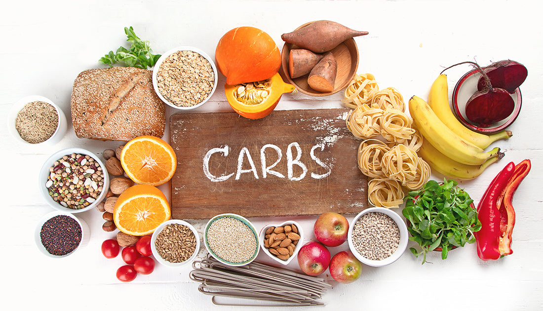 An assortment of natural foods including bowls of grains, beans, and fruits like banana and pumpkin, arranged on a table.