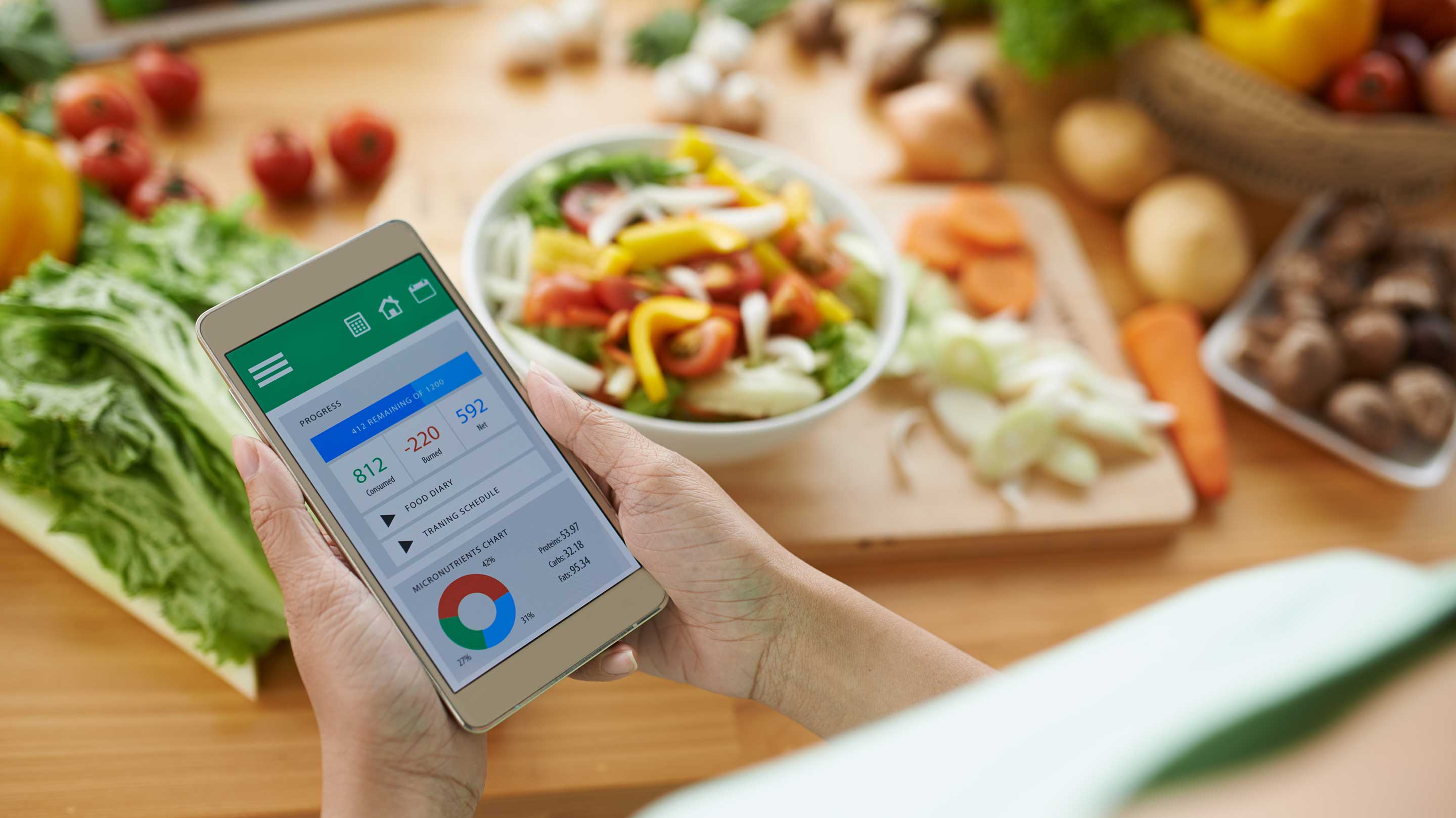 A person holds a phone displaying a chart, with a salad bowl in the background, emphasizing health and nutrition themes.