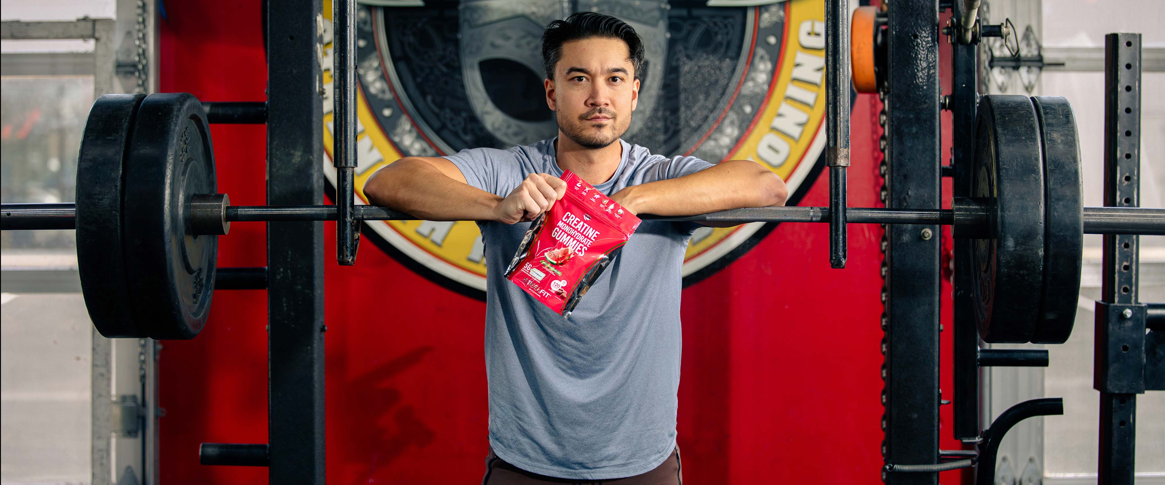 Man holding SteelFit creatine gummies at gym