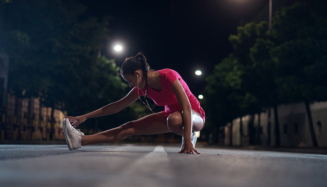 A woman stretches her leg on a street, showcasing flexibility and fitness, reflecting SteelFit USA's focus on health and sports performance.