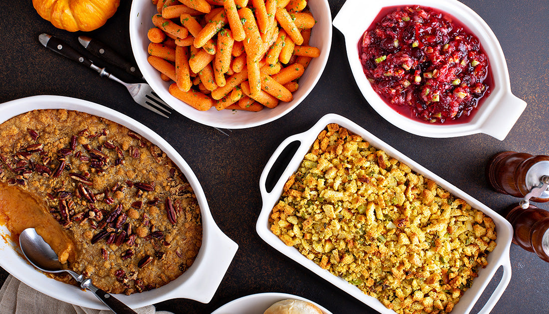 A table with various food dishes, including a bowl of carrots and a casserole with pecans, reflecting nutritious meal options.