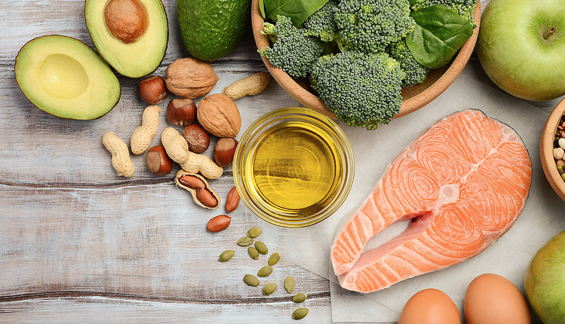 A table displays a green apple, broccoli, and a piece of salmon, ingredients aligned with health and fitness nutrition.