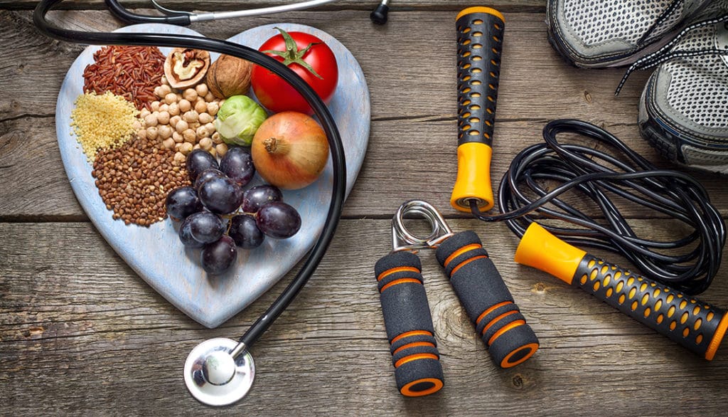 Heart-shaped plate with vegetables and fruits, jump rope, and hand grippers, reflecting a healthy lifestyle focus.