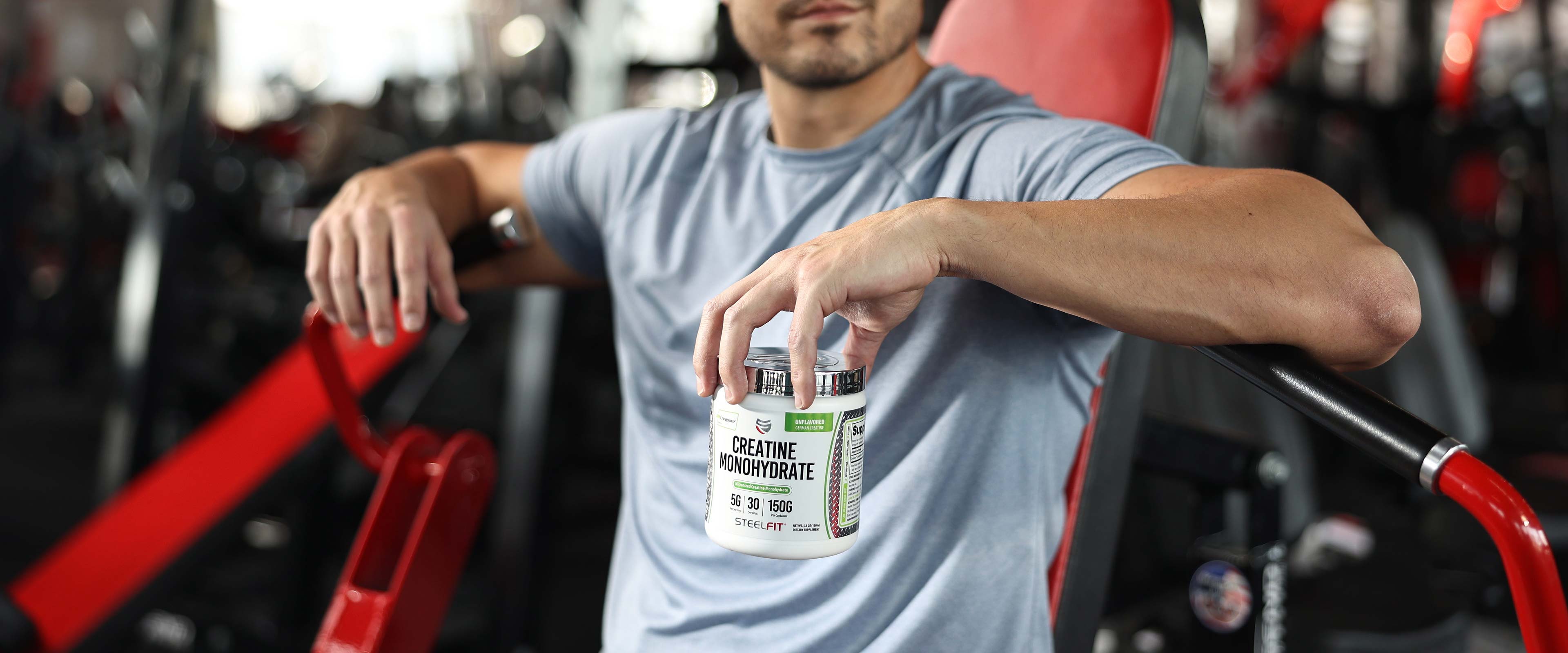 Man sitting with jar of creatine powder at gym
