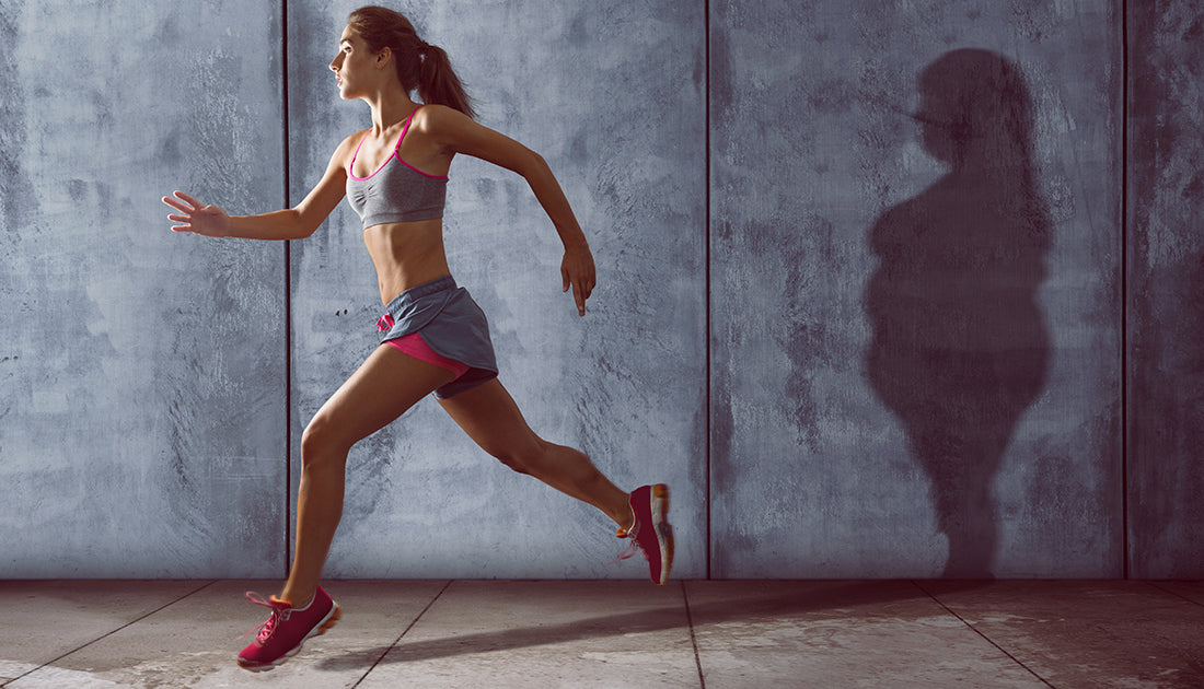 A woman in a grey tank top and shorts runs with a tennis racket, embodying fitness and agility, reflecting SteelFit USA's active lifestyle ethos.