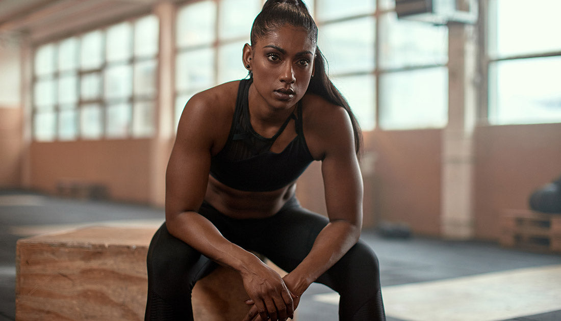 A woman seated, showcasing fitness attire, highlighting muscle definition, aligns with SteelFit USA's focus on health and fitness goals.