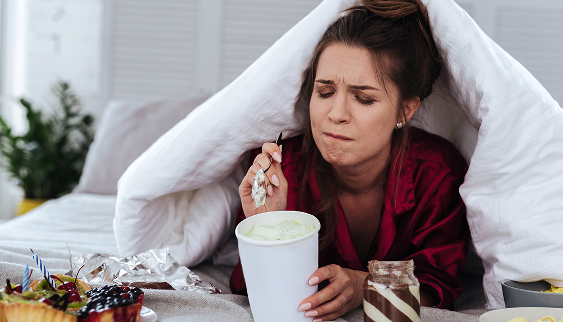 A woman enjoys yogurt under a blanket, highlighting relaxation and healthy nutrition, aligning with SteelFit USA's focus on health and fitness.