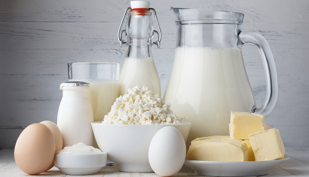 A variety of dairy products including a glass of milk, a bowl of cottage cheese, eggs, and a milk pitcher.