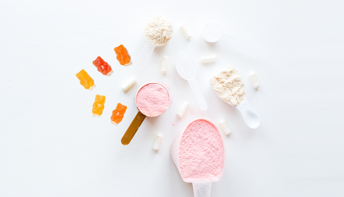 Spoons with various powders and gummy bears, representing sports nutrition supplements from SteelFit USA, emphasizing health and fitness goals.