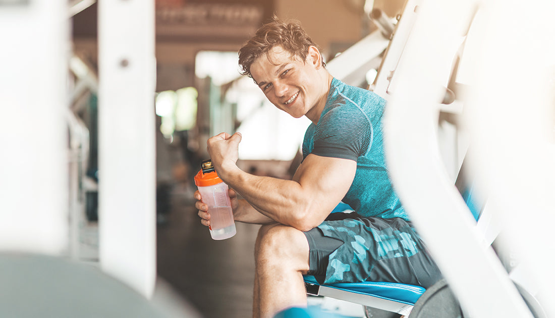 A man sitting on a bench holding a water bottle, embodying hydration and fitness, aligned with SteelFit USA's health and fitness focus.