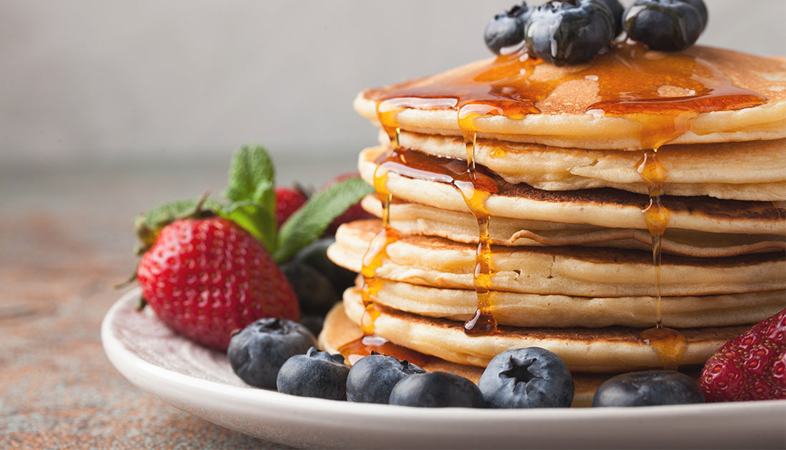 A stack of pancakes topped with syrup and strawberries, reflecting a delicious, health-conscious breakfast option.