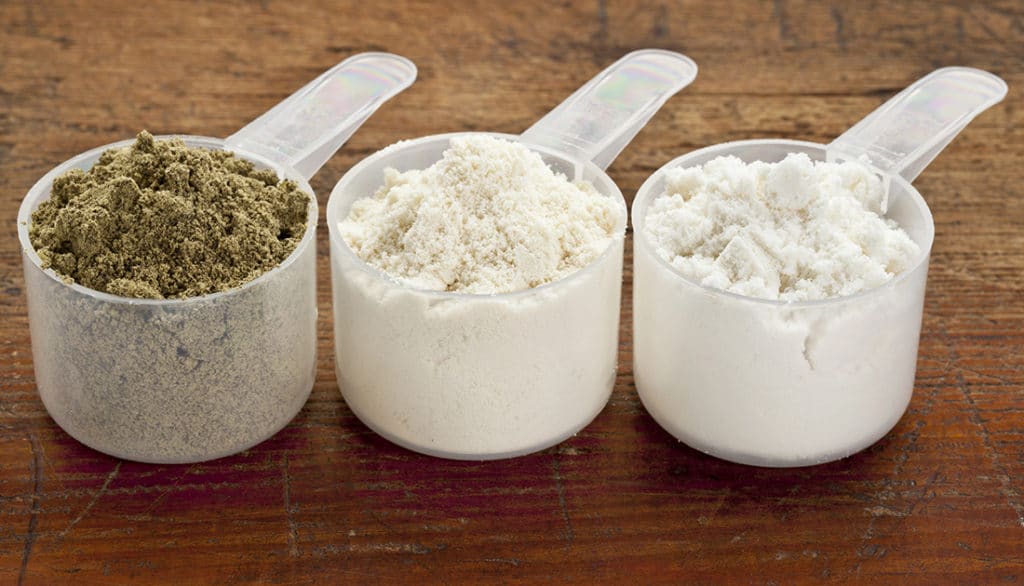 Assorted measuring cups with white and green powdered supplements, suitable for fitness and nutrition enhancement, reflecting SteelFit USA's product focus.