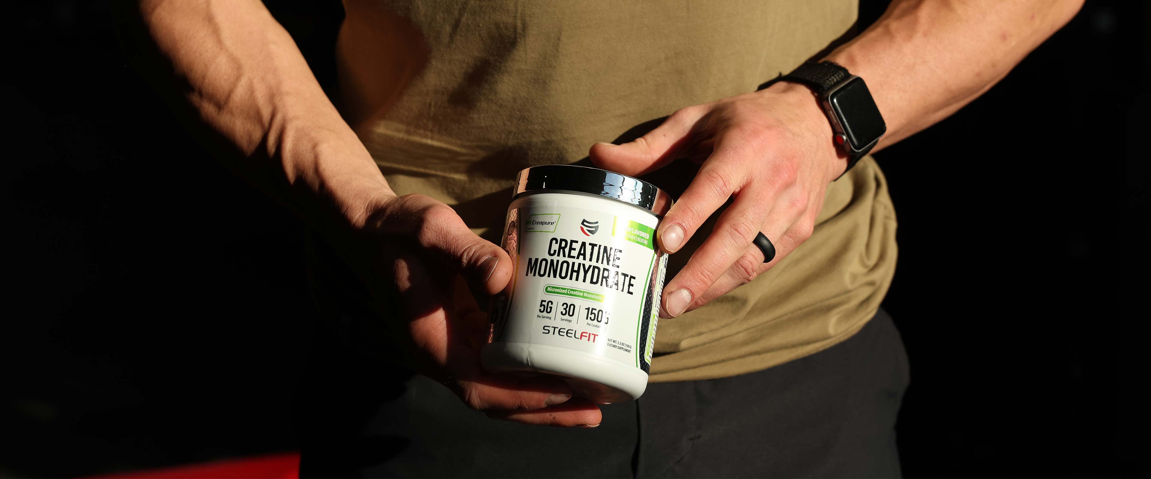 Man holding a jar of creatine monohydrate powder with Creapure from SteelFit