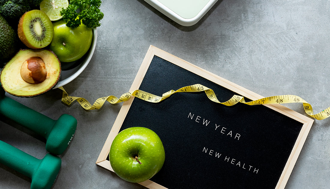 A chalkboard with a measuring tape and green apples, symbolizing healthy choices aligned with fitness and nutrition goals.