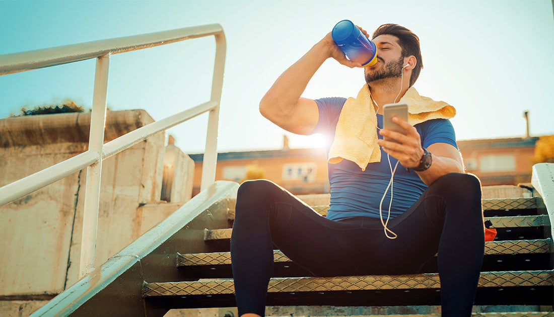 Man enjoying a protein shake using SteelFit shaker cup after working out in the sun