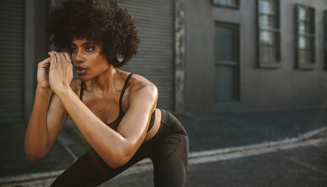 A woman in a black sports outfit squatting outdoors, embodying fitness and active lifestyle, aligned with SteelFit USA's health and fitness ethos.