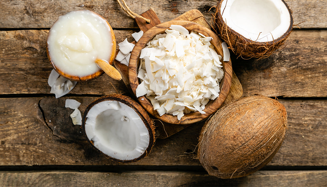 A bowl with coconut flakes and a halved coconut, emphasizing natural ingredients suitable for health and fitness-oriented nutrition.