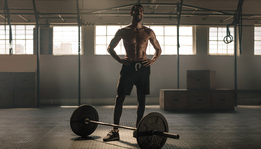 A shirtless man balancing on a barbell in a gym, exemplifying strength and fitness, aligned with SteelFit USA's health and fitness goals.