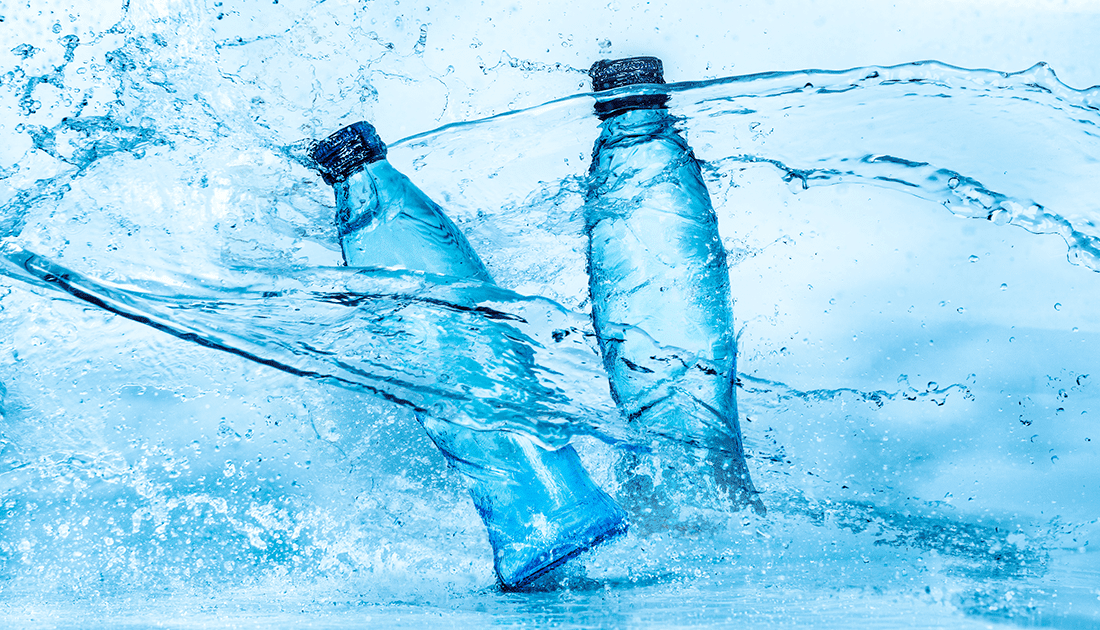 Two water bottles being hit with large splashes of water