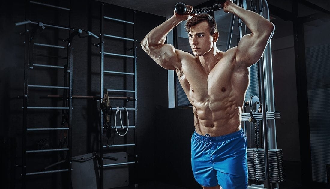 A man flexes his muscles while holding a bar, demonstrating strength and fitness, aligning with SteelFit USA's focus on muscle-building and health.