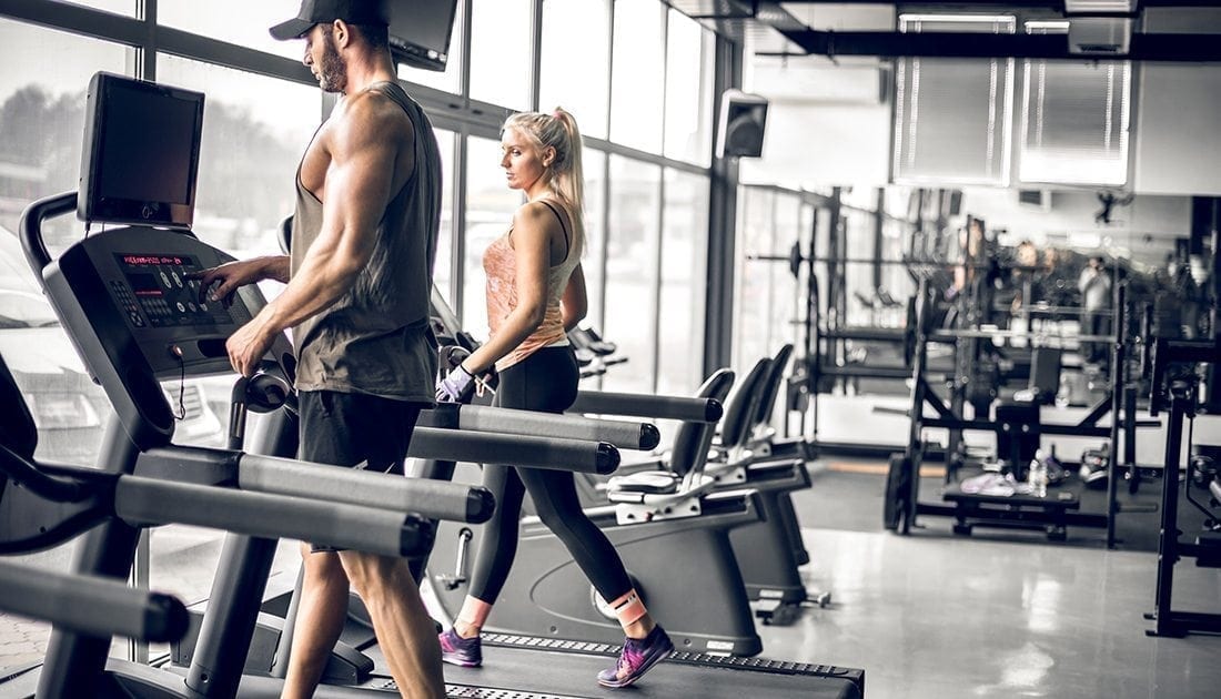 A man and woman walking on treadmills in a gym, illustrating fitness and exercise, aligning with SteelFit USA's health and fitness goals.