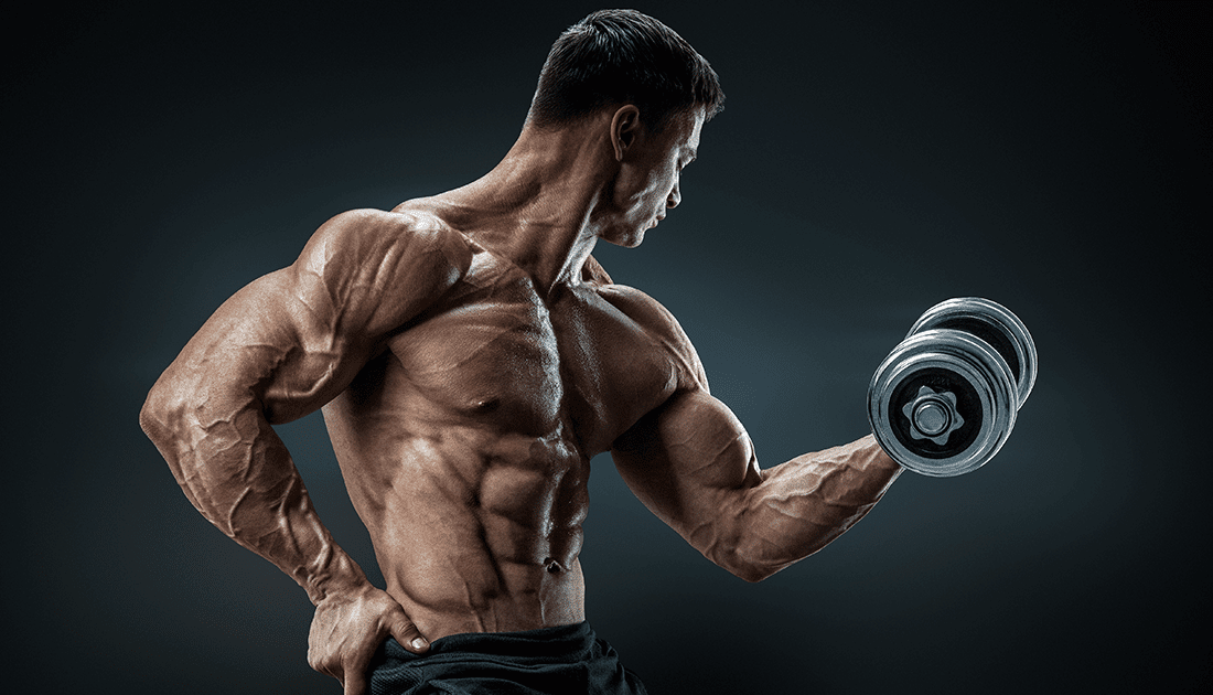 A muscular man flexes while holding a dumbbell, embodying fitness and strength, aligning with SteelFit USA's focus on achieving health and fitness goals.