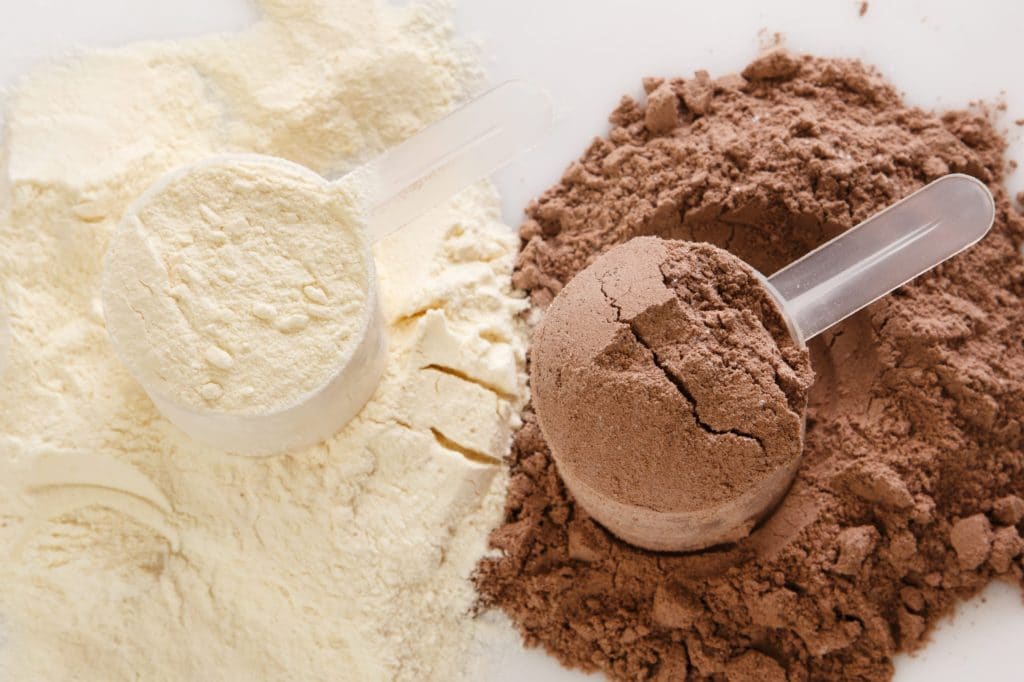 Two scoops of protein powder, one white and one brown, illustrating sports nutrition supplements available at SteelFit USA for fitness goals.