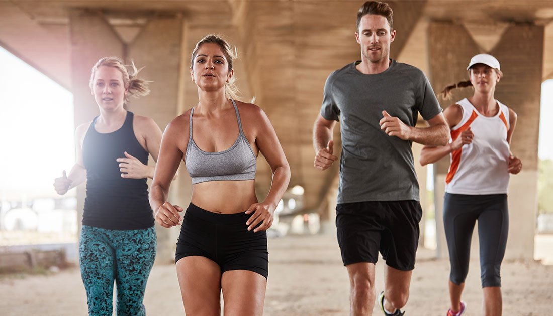 A group of people running indoors, showcasing athletic wear, highlighting fitness and health goals.