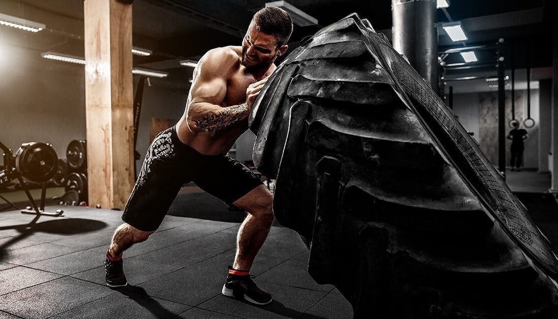 A man lifting a large tire indoors, showcasing strength and fitness, aligning with SteelFit USA's focus on health and fitness goals.