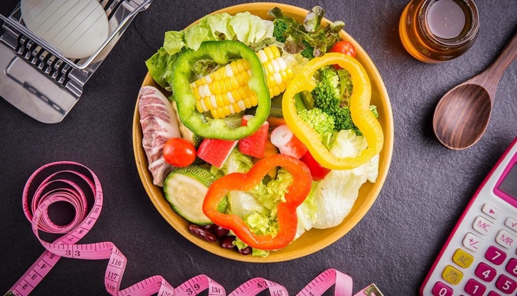 A bowl of fresh vegetables with a measuring tape, symbolizing health and fitness, aligned with SteelFit USA's nutrition focus.