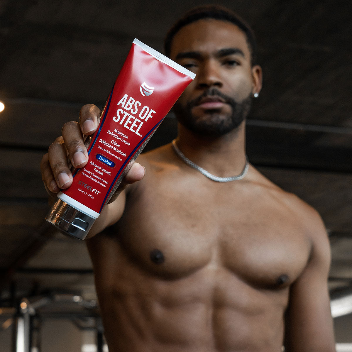 In shape male holding Abs of Steel topical fat burning cream by SteelFit