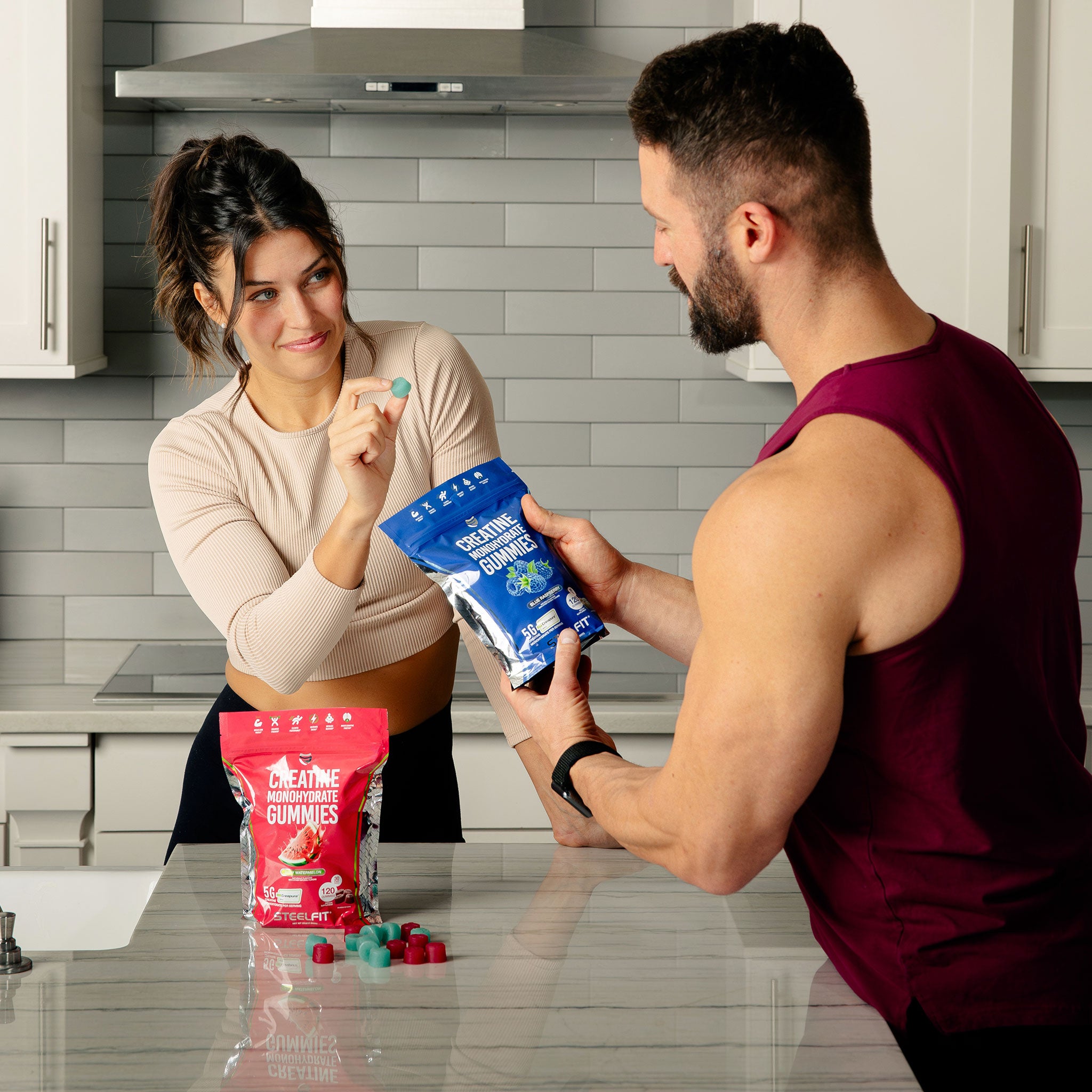 Couple in kitchen sharing a bag of SteelFit Creapure Creatine Monohydrate Gummies