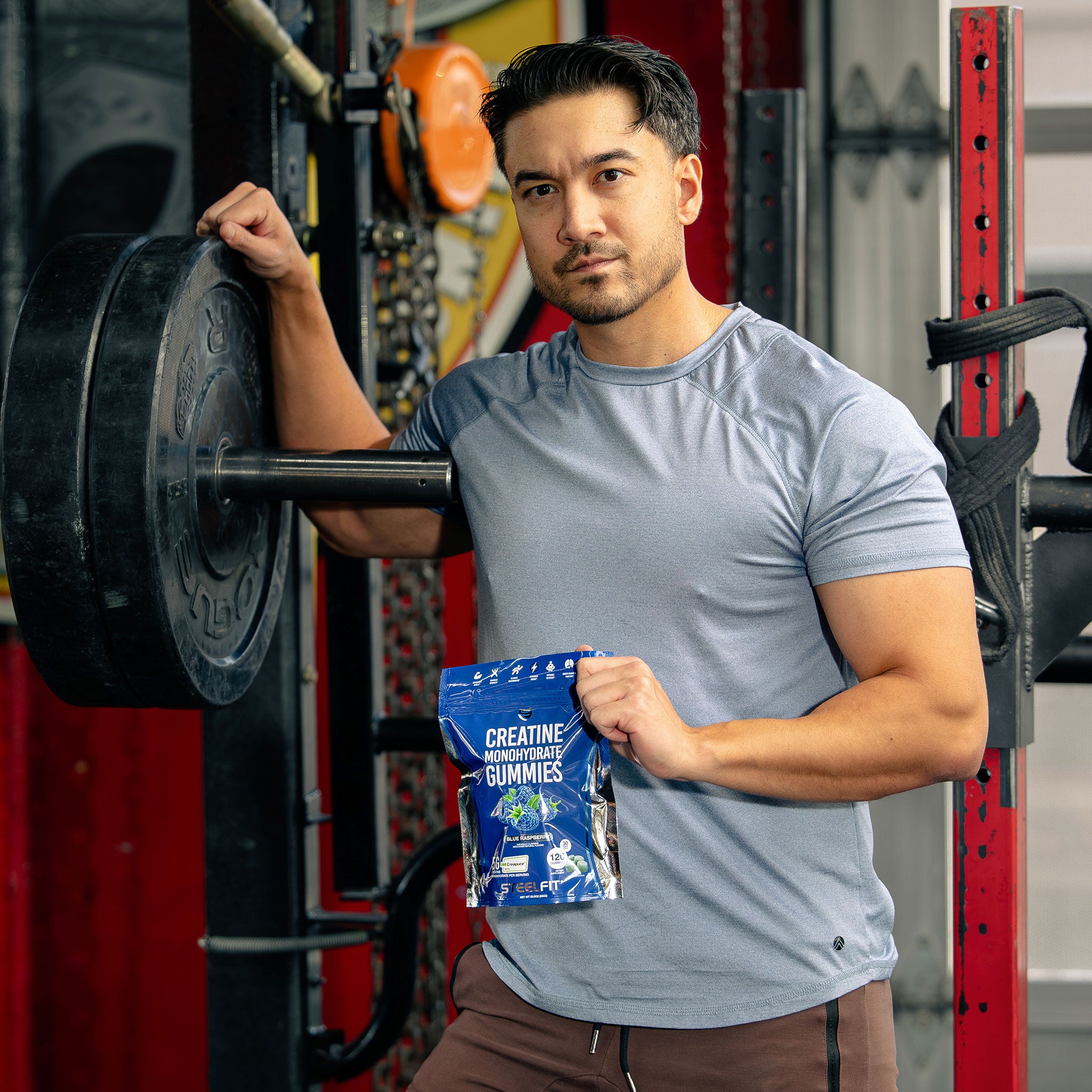 Man standing at gym looking at camera with creatine monohydrate gummies from SteelFit in his hand