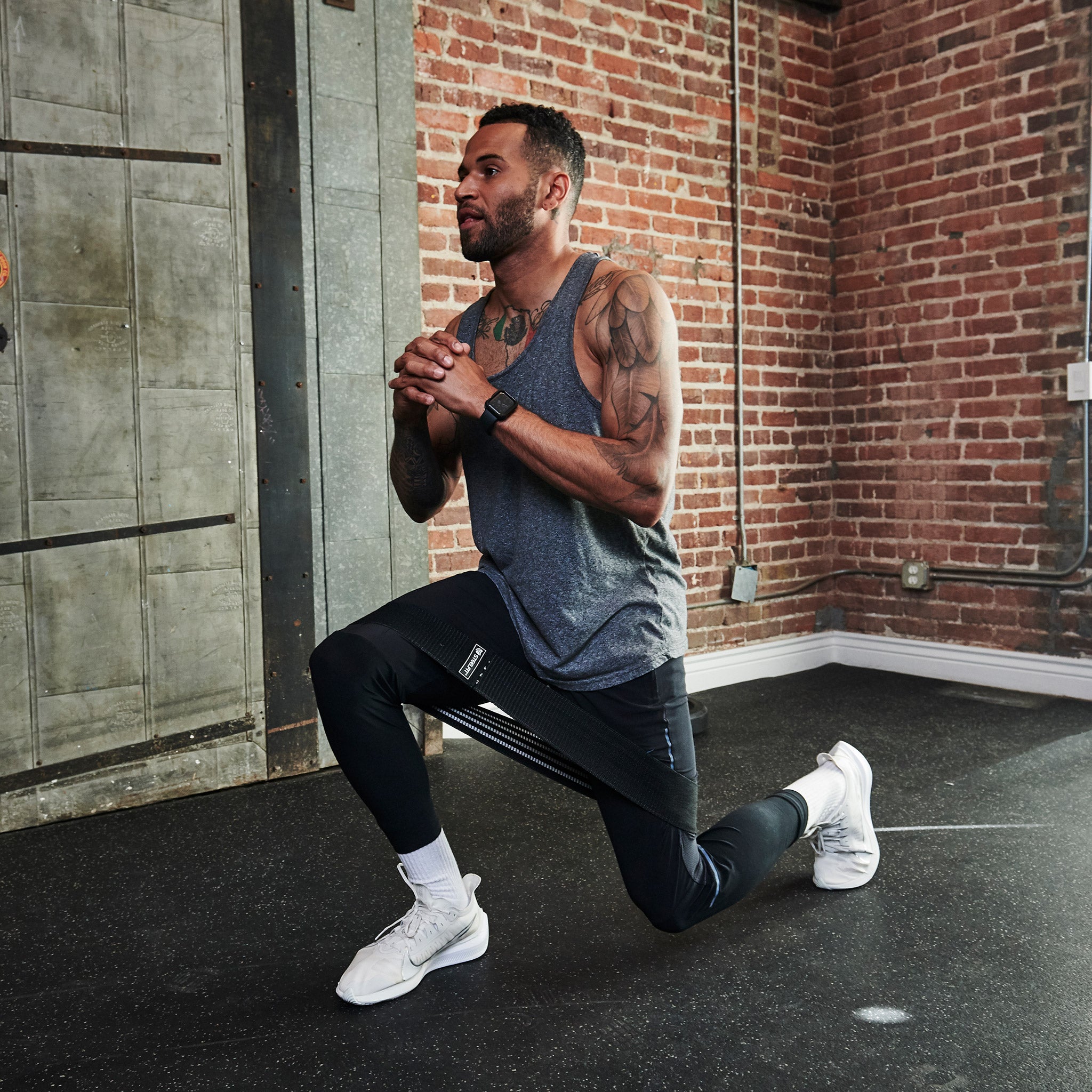 Man performing squats in a gym using a Hip Band for resistance training, showcasing its durable, soft-touch fabric and tension fit for effective muscle activation.